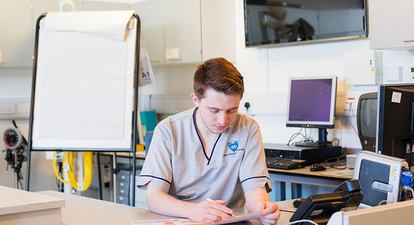 A Queen Margaret University Nursing student reading a chart