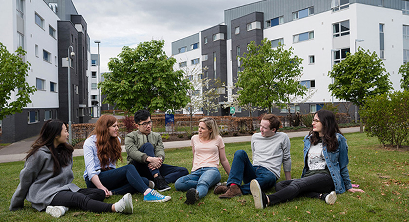 A group of students sitting down on the lawn at QMU