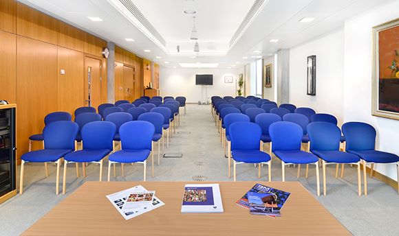 Long room with rows of blue chairs facing forward, QMU