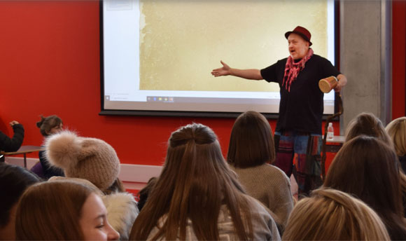 A man enthusiastically teaching a class of smiling students