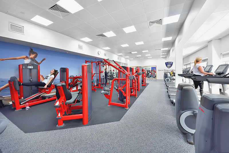 A quiet, well equipped gym with a handful of people working out at different stations