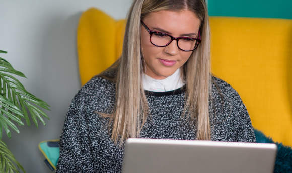 A Queen Margaret University student working on a laptop