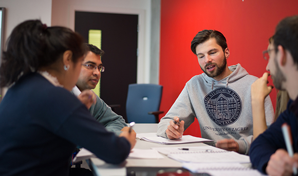 Group of  QMU students talking round a table and taking notes