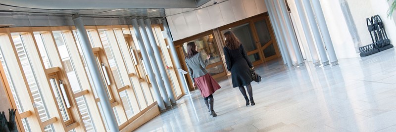 Two people walking in bright modern corridor