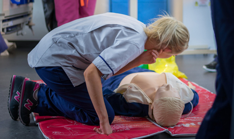 Queen Margaret University Nursing Student kneeling over a Resusci Annie doll