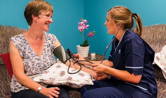 A student nurse taking a woman's blood pressure