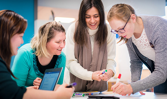 Four students working on a group project poster together