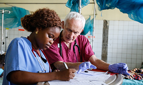 Two nurses sitting together in scrubs checking some paperwork