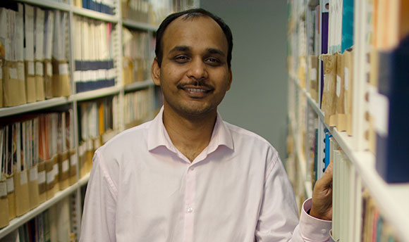 QMU student between bookshelves of campus library