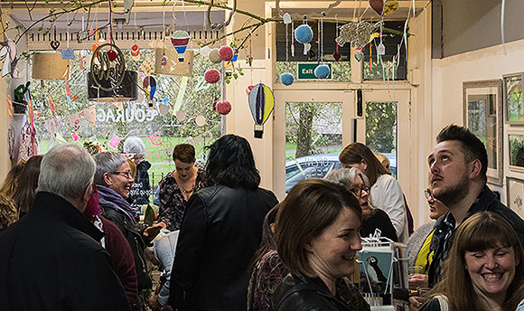 A busy store with art lining the walls and small decorations suspended from the roof