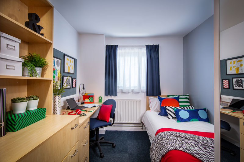 Inside a standard room, including a single bed, desk and chair 