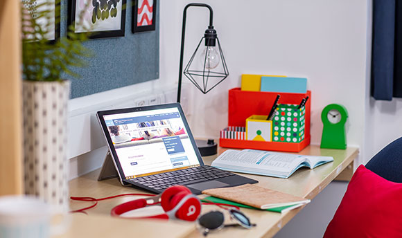 A laptop and headphones on a student desk in Queen Margaret University accommodation