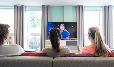 Three QMU students on the sofa in their accommodation watching tv