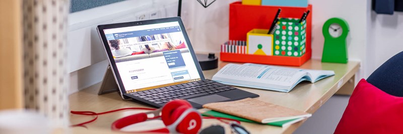 Student workspace with laptop and colourful stationery and earphones