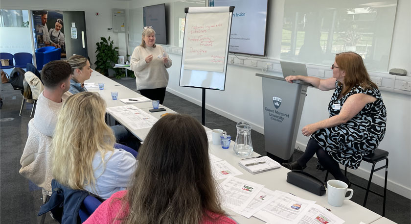 Members of the THRIVE programme deliver an educational session to a class full of people.