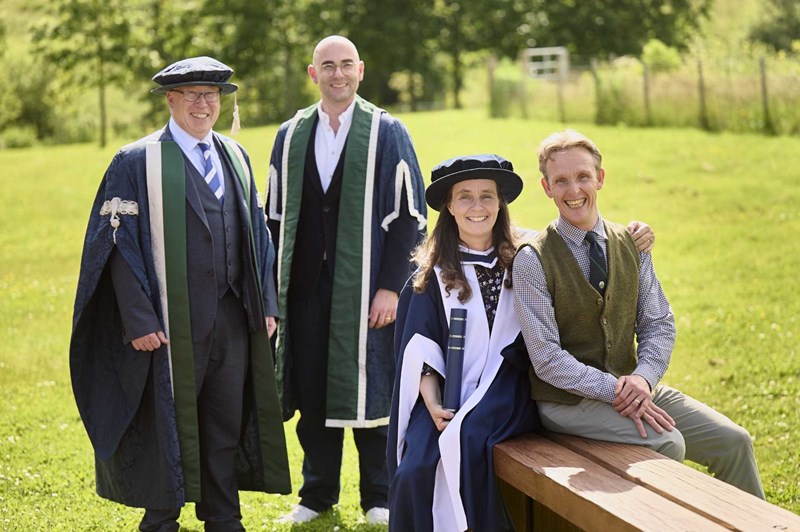 Juliet Roberts sitting on a wooden bench in her graduation gown and hat