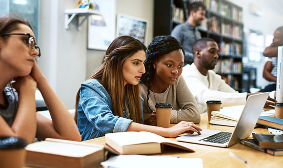 Shot of two young women using a laptop together in a college library