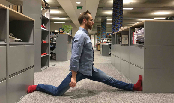 Anthony fitting himself in the space between two desks