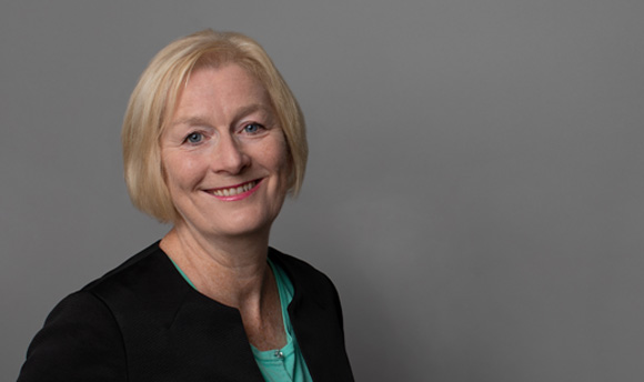 A woman with short blonde hair smiles towards the camera