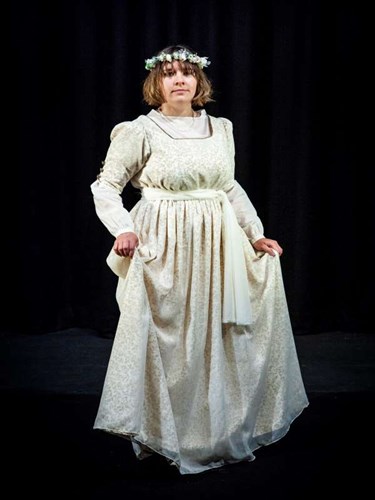 Performer on stage wearing long white dress and flower headband