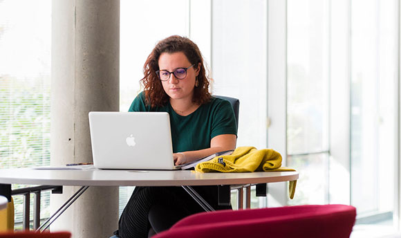 Student using a laptop within the university library