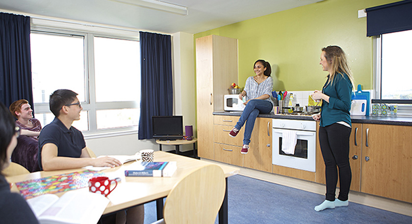 Students in their shared kitchen chatting and studying