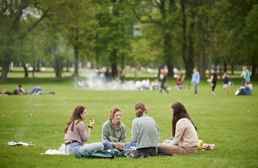 A group of four young women enjoying a picnic in the grass in the Meadows area of Edinburgh