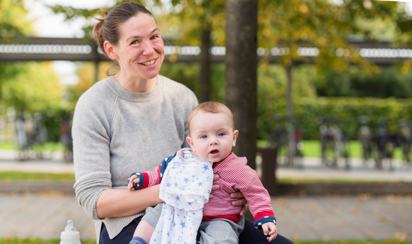 QMU student sitting in University Square with baby